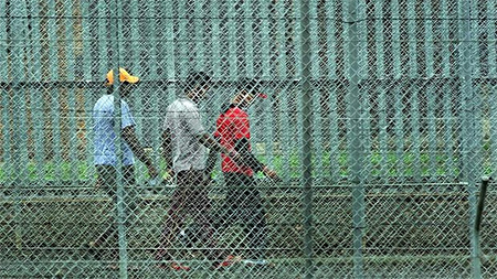 People walk behind the barbed wire fences at the Villawood Immigration Detention Centre in Sydney 
